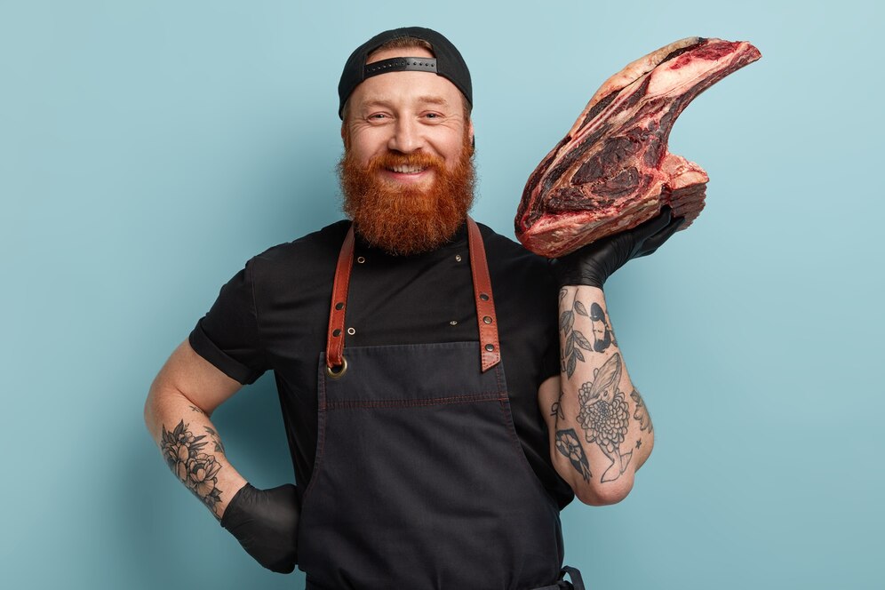 man-with-ginger-beard-apron-gloves-holding-meat